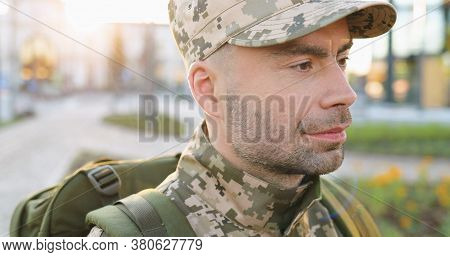 Portrait Of Serious Caucasian Handsome Young Male Soldier In Cap With Backpack Standing At Street. M