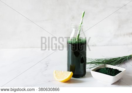 Spirulina Drink With Lemon And Spirulina Algae Powder On White Marble Table.