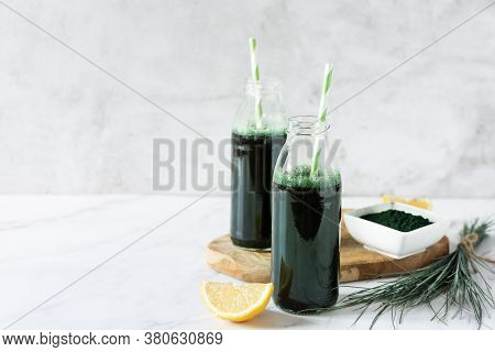 Spirulina Drink With Lemon And Spirulina Algae Powder On White Marble Table.