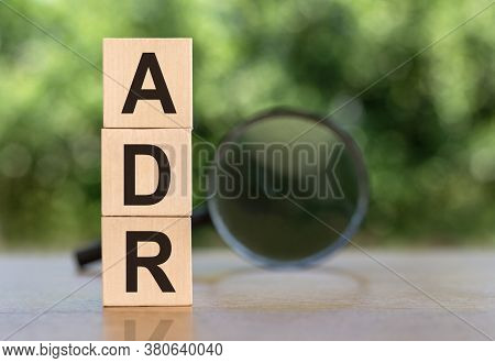 Adr Abbreviation On Wooden Blocks On Table With Magnifier On Green Background