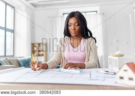 architecture, building, construction and real estate concept - african american female architect with blueprint, ruler and living house model on table working at home office