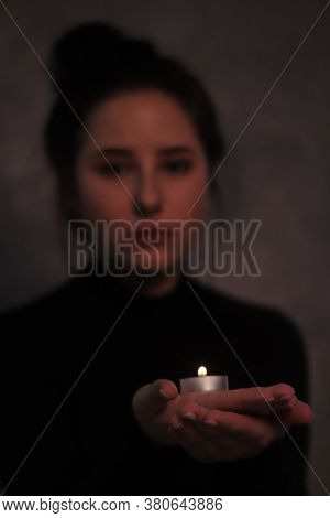 Dark Portrait Of A Sad Brunette Girl Almost Burst Into Tears In A Black Turtleneck Holding Candle Ag