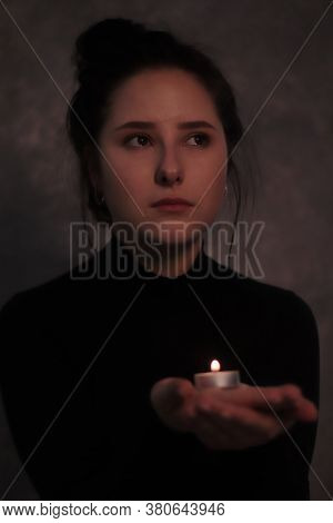 Dark Portrait Of A Sad Brunette Girl Almost Burst Into Tears In A Black Turtleneck Holding Candle Ag