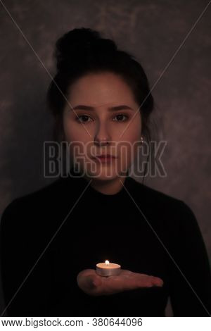 Dark Portrait Of A Sad Brunette Girl Almost Burst Into Tears In A Black Turtleneck Holding Candle Ag