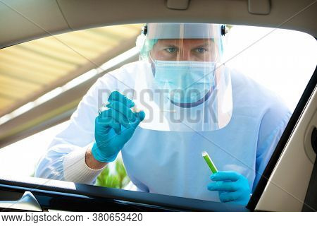 Medical staff with PPE suit testing patient at a Covid-19 drive thru by throat swab. Health care drive thru service and medical concept