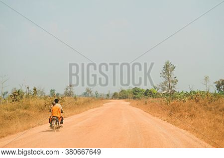 Motorcyclist Giving Ride to Young Monk on Rural Road