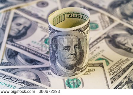 Roll Of 100 Dollar On The Many Dollars Background. High Resolution.