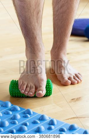 man doing flatfoot correction gymnastic exercise using massage roller at home