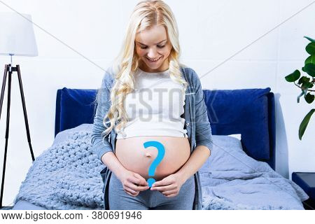 Young Woman Is Holding Blue Paper Question Sign Near Abdomen, Big Pregnant Female Belly. Ultrasound 