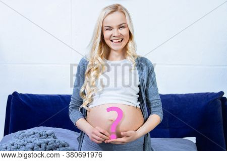 Young Woman Is Holding Pink Paper Question Sign Near Abdomen, Big Pregnant Female Belly. Ultrasound 