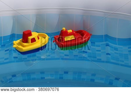 Bright Colored Toy Boats Float In The Home Pool