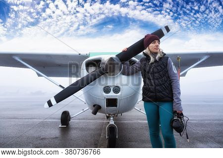 Young Caucasian Female Student Pilot Is Standing In Front Of A Single Engine Airplane At The Airport