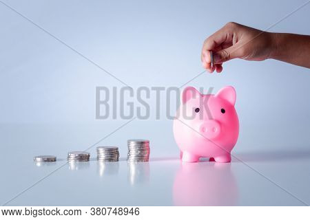 Hand Of Kid Holding Coin Put In Piggy Bank With Money Stack Growing Growth Saving Money, Concept Inv