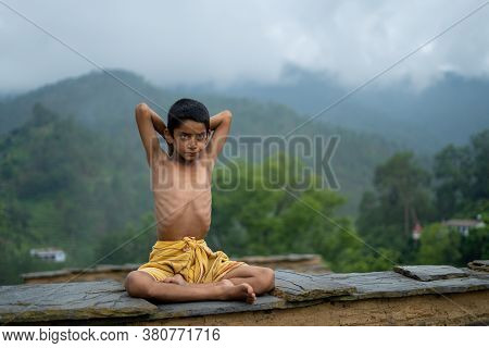 A Young Indian Cute Kid Doing Yoga In The Mountains,wearing A Dhoti