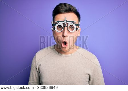 Young handsome caucasian man wearing optometrical glasses over purple background afraid and shocked with surprise expression, fear and excited face.