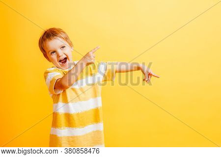 Boy Smiling And Pointing Aside Reccomending To Buy Something On Yellow Background