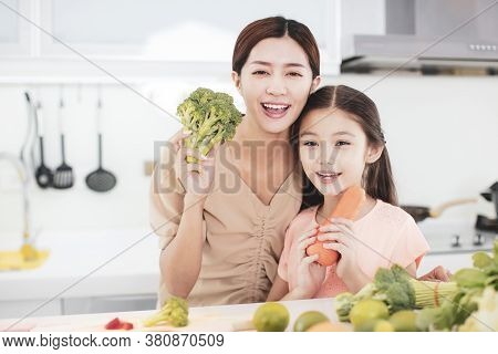 Happy Mother And Child Daughter  Preparing The Vegetables And Fruit In Kitchen