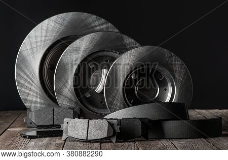 Row Of Brake Discs And Friction Pads On Rustic Wooden Table