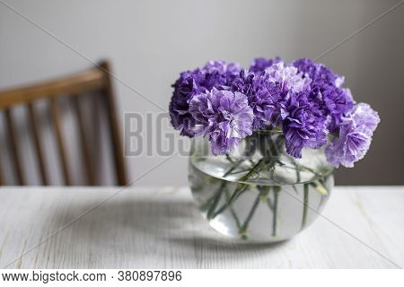 Bridal Bouquet Of Lilac Carnations In A Round Glass Vase As Table Decoration