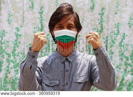 Bulgaria Flag On Hygienic Mask. Masked Asian Man Prevent Germs And Wear Blue Long Sleeved Shirt. Tin