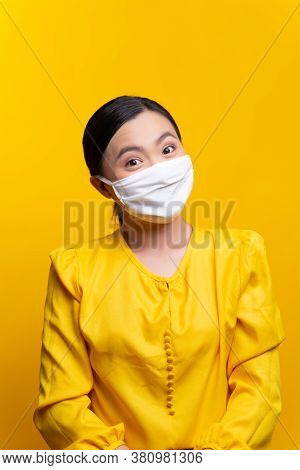 Asian Woman Wearing Protective Face Mask Isolated On Yellow Background.