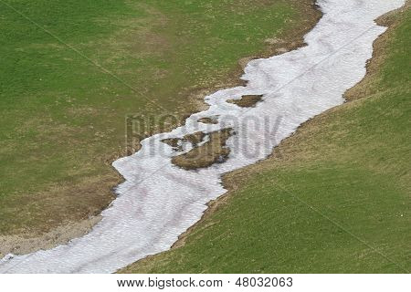 Nevaio e prato verde