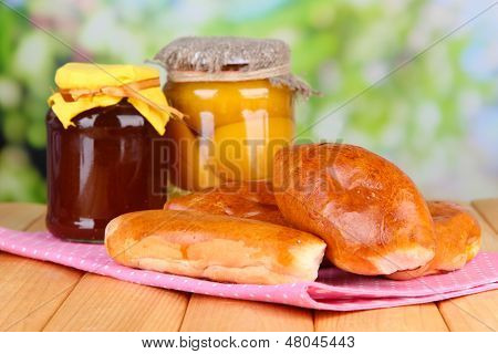 Empanadillas al horno frescos con mermelada de frutas, en la mesa de madera, sobre fondo brillante