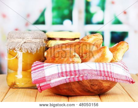 Empanadillas al horno frescos con mermelada de frutas, en la mesa de madera, sobre fondo brillante