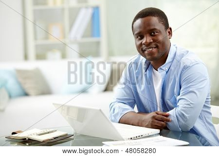 Obraz africký mladík při pohledu na fotoaparát s laptopem nedaleko od