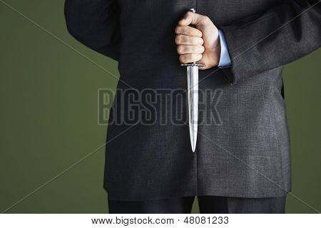 Vértes midsection gazdaság mögött vissza kés ellen zöld háttér üzletember