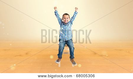 Lucky Boy On A Wooden Chair Over Ocher Background