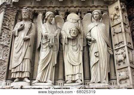 PARIS, FRANCE - NOV 05, 2012: Emperor Constantine, angel, St Denis holding his head, and angel, detail of Notre Dame cathedral. The Portal of the Virgin, dedicated to the patroness of the cathedral.
