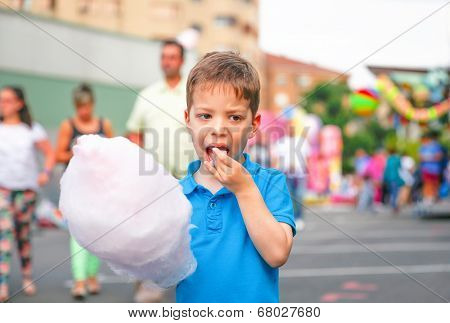 Cute kid eating cotton candy over fair background