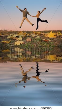 jump couple. autumn leaves. sunset water
