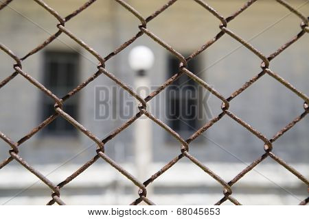 Rustic Metal Chainlink Fence With A Window And Light Pole In Background
