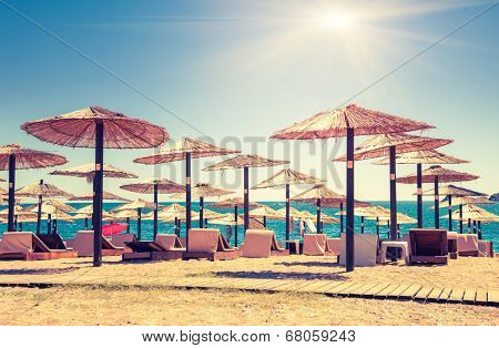 Thatched umbrellas and beach chairs on the beach. Budva, Montenegro, Balkans, Europe. Beauty world. Retro style filter. Instagram toning effect.