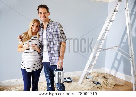 Portrait Of Couple Decorating Nursery For New Baby