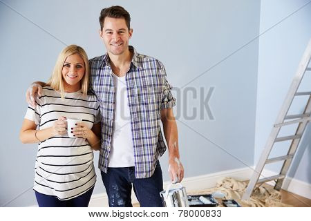 Portrait Of Couple Decorating Nursery For New Baby