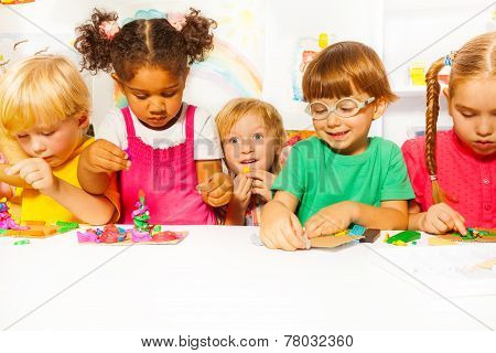 Group of kids in kindergarten play with plasticine