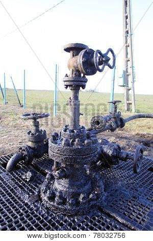 ARAD, ROMANIA - FRIDAY, DECEMBER 5, 2014: Oil leaks from a surface well head at a production field operated by OMV Petrom S.A, the largest gas and oil producer in Eastern Europe 