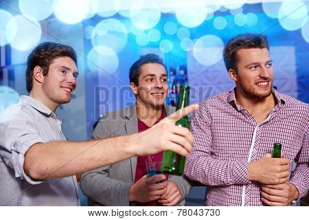 nightlife, party, friendship, leisure and people concept - group of smiling male friends with beer bottles drinking in nightclub