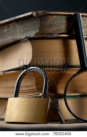 Pile Of Old Books With Keylock And Magnifying Glass