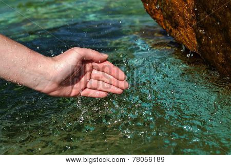 Beautiful woman hand in clear mountain water