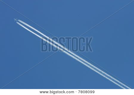 Flygande Airoplane på den blå himlen lämnar vita linjer bakom