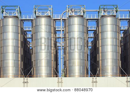 Metal Steel Tank Storage In Heavy Industry Estate Plant Against Clear Blue Sky Use For Industrial An