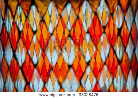 blurred detail of multicolored stained glass with irregular diamond block pattern