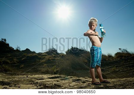 Boy Standing In The Sand Holding A Water Bottle Showing Muscle