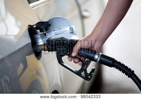 Silver car at gas station being filled with fuel