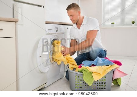 Man Putting Dirty Clothes Into The Washing Machine