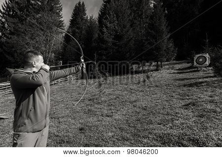 A man shoots a bow. Man engaged in archery.